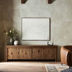 a living room with a chair, table and large painting on the wall above it