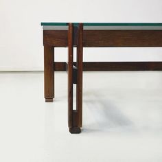 a wooden table with glass top sitting on a white floor