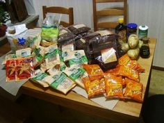 a wooden table topped with lots of bags of food and condiments on top of it