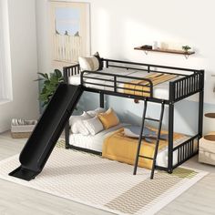 a black bunk bed with a slide in the middle and pillows on the floor next to it