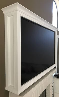 a flat screen tv mounted to the side of a white fireplace with an arched window