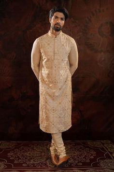 Beige silk kurta with all over hand done french knot embroidery with mustard and maroon highlights. Comes along with churidar.
Components: 2
Pattern: Embroidery
Type Of Work: French Knots
Neckline: Stand Collar
Sleeve Type: Full Sleeves
Fabric: Silk
Color: Beige
Other Details: 
Concealed button placket
Occasion: Sangeet - Aza Fashions Bollywood Style Festive Nehru Jacket With Gold Embroidery, Traditional Gold Embroidered Churidar For Festive Occasions, Festive Bollywood Nehru Jacket With Gold Embroidery, Festival Sherwani With Resham Embroidery In Dola Silk, Traditional Churidar With Gold Embroidery For Festivals, Gold Embroidered Straight Kurta Bandhgala, Designer Bandhgala With Gold Embroidery Straight Kurta, Festival Dola Silk Sherwani With Resham Embroidery, Traditional Festive Churidar With Gold Embroidery