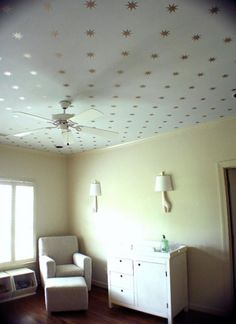 an empty room with a chair, dresser and ceiling star decorations on the ceiling above it