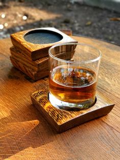 a glass of whiskey sitting on top of a wooden table next to an empty container