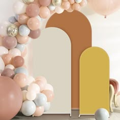 an arch is surrounded by balloons and other decorations in pastel colors on the wall