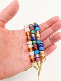 a hand holding a bracelet with multi colored beads