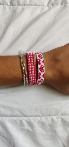 a woman's arm with three bracelets on it and one is wearing a red and white checkered shirt