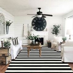 a living room filled with furniture and a clock mounted to the wall above it's fireplace