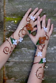 two hands with bracelets and flowers on them