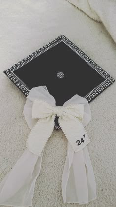 a black and white graduation cap with a bow on the front sitting on a carpet