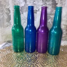 three different colored glass bottles sitting on top of a doily covered tablecloth,