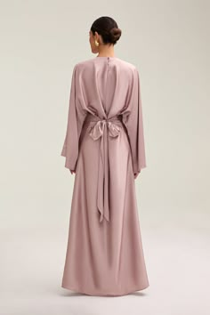 Indulge in luxury with the Batool Satin Maxi Dress. Its loose wide sleeves and lustrous satin fabric exude elegance, while the adjustable tie waist flatters your figure. Versatile design makes it perfect for Eid and beyond. Elevate your style with this exclusive piece. Model is 5'7 wearing size XS/58" Elegant Long Sleeve Dress With Tie Fastening, Modest Graduation Dress Hijab, Flowy Tie Waist Dress For Formal Occasions, Formal Flowy Dress With Tie Waist, Elegant Wrap Maxi Dress With Draped Sleeves, Evening Wrap Maxi Dress With Tie Waist, Elegant Long Sleeve Dress With Tie Sleeves, Elegant V-neck Wrap Dress With Tie Fastening, Chic Wrap Dresses With Tie Back