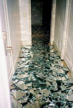 a hallway that has broken glass on the floor and is littered with shattered pieces,