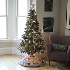 a small christmas tree in a living room next to a chair and pictures on the wall