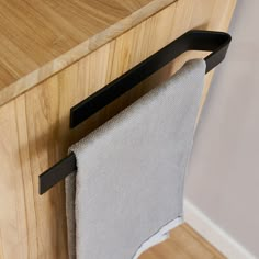 a towel hanging on the handle of a wooden cabinet with a gray cloth draped over it