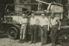 four men standing in front of an old fire truck