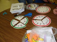 children are sitting at a table with clocks and pencils in front of the clock