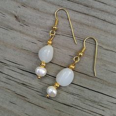 "Two classic jewels in brilliant white: milky white Peruvian opals are paired with white freshwater pearls in a stunningly classic look 💕  These are the perfect jewelry gift for someone with a birthday in June (birthstone= pearl!) or October (birthstone= opal!). 💕 Peruvian opals 💕 Freshwater pearls 💕 22K gold-plated wires & accents This pair of opals are milky white and faintly translucent.  Their faint bluish-white shade is more noticable against the creamy white of the pearls. Did you know Classic White Birthstone Earrings, Classic White Mother Of Pearl Earrings, White Oval Pearl Earrings, Classic White Gemstone Earrings, Delicate White Opal Jewelry, Classic White Opal Jewelry, White Elegant Pearl Earrings, Elegant White Gemstone Pearl Earrings, White Pearl Charm Earrings