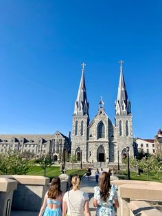 two girls are walking towards an old church with steeples on it's sides