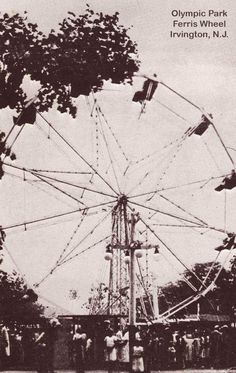 an old ferris wheel with people standing around it