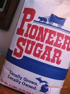 a bag of planter's sugar sitting on top of a wooden table next to a potted plant