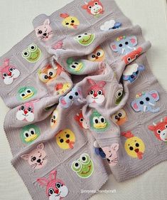 a knitted baby blanket with many cartoon animals on it's sides and an animal - themed scarf around the edges