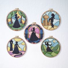 four round stained glass ornaments depicting the silhouettes of people in different colors and sizes