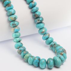 a necklace made with turquoise beads on a white surface