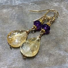 IndigoLayne, handcrafted in the Pacific Northwest, Citrine Amethyst gemstone earrings. Sunshine color of citrine drops with deep purple amethyst gems, 6 mm rondelles. Adorned with daisy flower spacers, they hang 32 mm/ from bottom of 14 K gold filled Shepherd hook ear wires. A nice gift. - each earring weighs 1.5 g  Arrives gift wrapped in our IndigoLayne signature box. Direct Shipping/Personal Note, at checkout, please leave your message. INTERNATIONAL CLIENTS : buyer is responsible for any in country fees. Home: https://www.etsy.com/shop/IndigoLayne  Thank you for your visit,  Sissy  © Sissy Altom 2021 - *Artist Copyright Handmade Gold Long Drop Crystal Earrings, Gold Teardrop Earrings With Gemstone Accents, Gold Teardrop Gemstones, Gold Briolette Teardrop Handmade Earrings, Yellow Gold Amethyst Teardrop Earrings, Handmade Gold Briolette Teardrop Earrings, Gold Crystal Earrings With Gemstone Accents As Gift, Gold Amethyst Long Drop Earrings, Handmade Gold Amethyst Earrings