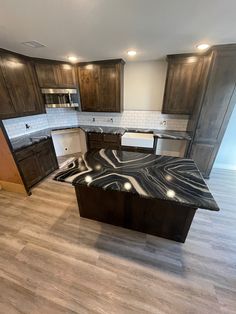 an empty kitchen with marble counter tops and wooden cabinets in the middle of the room