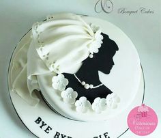 a white cake decorated with a silhouette of a woman's head and pearls on it