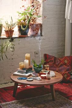 a coffee table with plants and candles on it