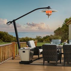 an outdoor dining table and chairs on a deck overlooking the ocean with a lamp over it