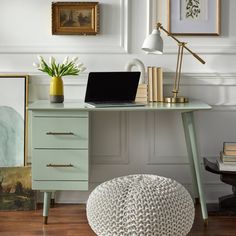 a laptop computer sitting on top of a desk next to a vase with flowers in it