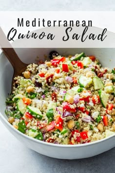 mediterranean quinoa salad in a white bowl with a wooden spoon on the side