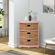 a pink dresser with wicker drawers in a white living room next to a window