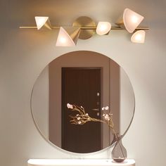 a round mirror with three candles on it in front of a wall mounted light fixture