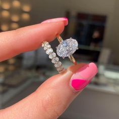 a woman's hand holding a diamond ring with pink and white nail polish on it