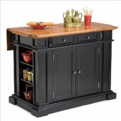 a black kitchen island with wooden top and two cupboards on one side, in front of a white background