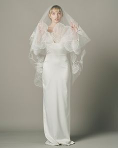 a woman in a white wedding dress with a veil on her head and hands up