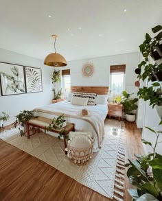 a bedroom with white walls, wooden floors and lots of greenery on the bed