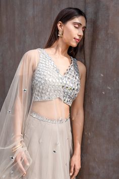 Grey blouse featuring all-over mirror work and cutwork neckline hem. Paired with high waisted lehenga featuring mirror embellishments and embroidered dupatta with tassels.
Component: 3
Pattern: Embroidered
Type Of Work: Mirror
Neckline: V-Neck
Sleeve Type: Sleeveless
Fabric: Net, Shantoon
Color: Grey
Other Details: 
Cutwork blouse hem and lehenga band
All-over mirror embellishments
Back tassel tie-up blouse
Tassel hem dupatta
Occasion: Wedding, Sangeet, Mehendi and Haldi - Aza Fashions Mirror Lehenga, Mirror Blouse, Glam Mirror, Mirror Work Lehenga, Mirror Work Blouse, Grey Mirror, Work Lehenga, Net Lehenga, Indian Wedding Wear