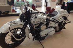 a white motorcycle is on display in a room with other items and decorations around it