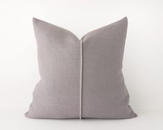 a gray pillow with white zippers on it