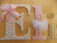 the letters are decorated with pink and gold accents, such as a ballerina's tutu