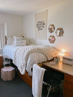 a bedroom with a bed, desk and chair next to a wall hanging on the wall