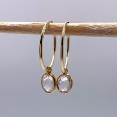 Clear quartz (rock crystal) oval crystal gemstone (7x9mm) drop earrings on 22 Carat gold vermeil medium hoop (20mm wide) sleeper ear wires. Sleeper ear wires are tubular in design with one end slotting a little into the other to form an endless ring. They are lightweight and uncomplicated. Vermeil is a high quality form of gold plating in which a thick layer of gold (this must be more than 2.5 microns and between 14 Carat and 22 Carat) is coated over 925 Sterling Silver. Shipped inside a white l Handmade Paper Boxes, Quartz Rock, 22 Carat Gold, Les Chakras, Wedding Gifts For Bridesmaids, Rock Crystal, March Birth Stone, Crystals And Gemstones, Healing Stones