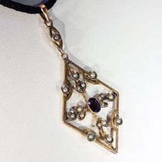 During the Edwardian era, feminine motifs with delicate yet understated designs were considered en vogue. Natural pearls, amethysts, peridots, aquamarines, and other semi-precious stones were worn by affluent women to complement the trend of donning white silk and lace. This jewelry movement differed from the larger and dark colored jewels of the later Victorian era, it was a fresh and welcome change that breathed life back into fashion. This pendant would have been incredibly stylish for its ti Purple Amethyst Jewelry With Rose Cut Diamonds, Elegant Amethyst Jewelry, Victorian Wedding Jewelry With Gemstone Accents, Gift Jewelry With Rose Cut Diamonds And Amethyst, Elegant Hallmarked Gemstones For Jewelry Making, Rose Cut Amethyst Jewelry For Wedding, Purple Diamond Jewelry With Rose Cut, Elegant Yellow Gold Amethyst Jewelry, Purple Diamond Jewelry With Rose Cut Diamonds