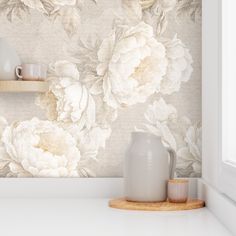 a white vase sitting on top of a counter next to a cup and saucer