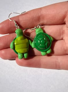 two little green turtle keychains sitting on top of each other's fingers